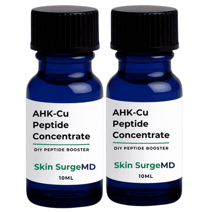 Two 10ml cobalt blue glass bottles of Skin SurgeMD AHK-Cu Peptide Booster Liquid Concentrate with black ribbed caps and white labels, shown side-by-side on a white background.