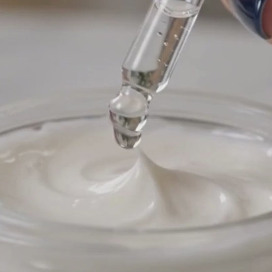 Close-up of Skin SurgeMD Argireline Peptide Booster Concentrate being added to a white face cream with a dropper, demonstrating how to customize skincare with a concentrated anti-aging peptide booster.